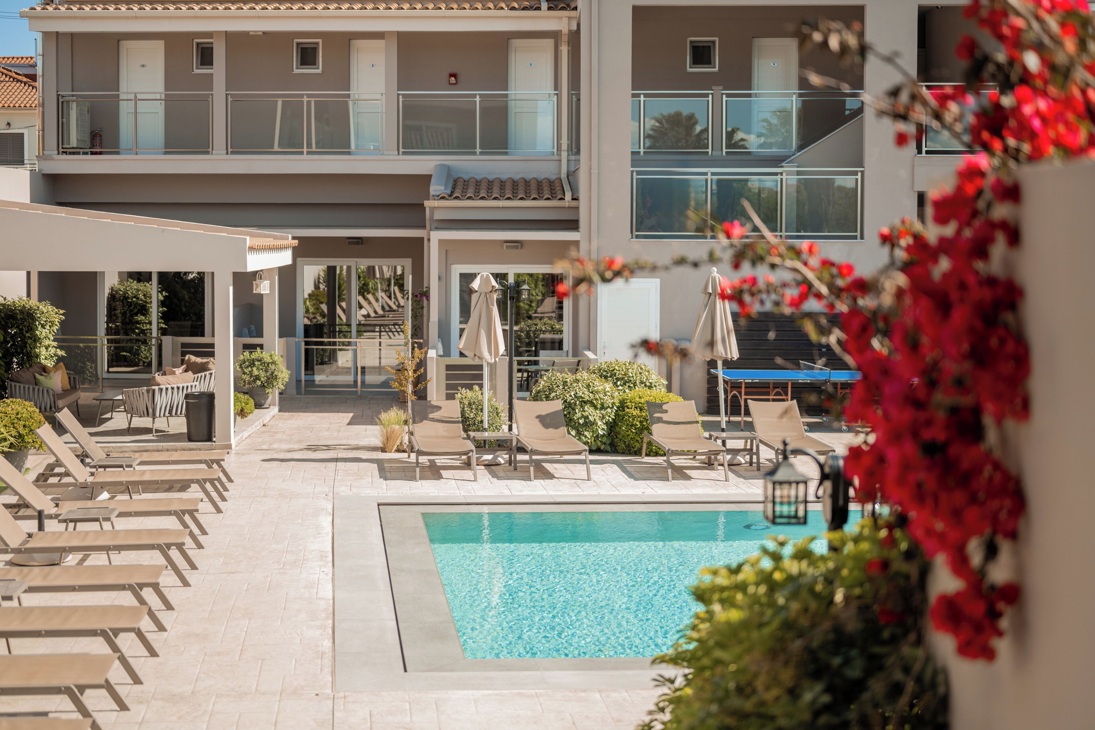 Un hotel con piscina, lettini e una zona relax coperta.