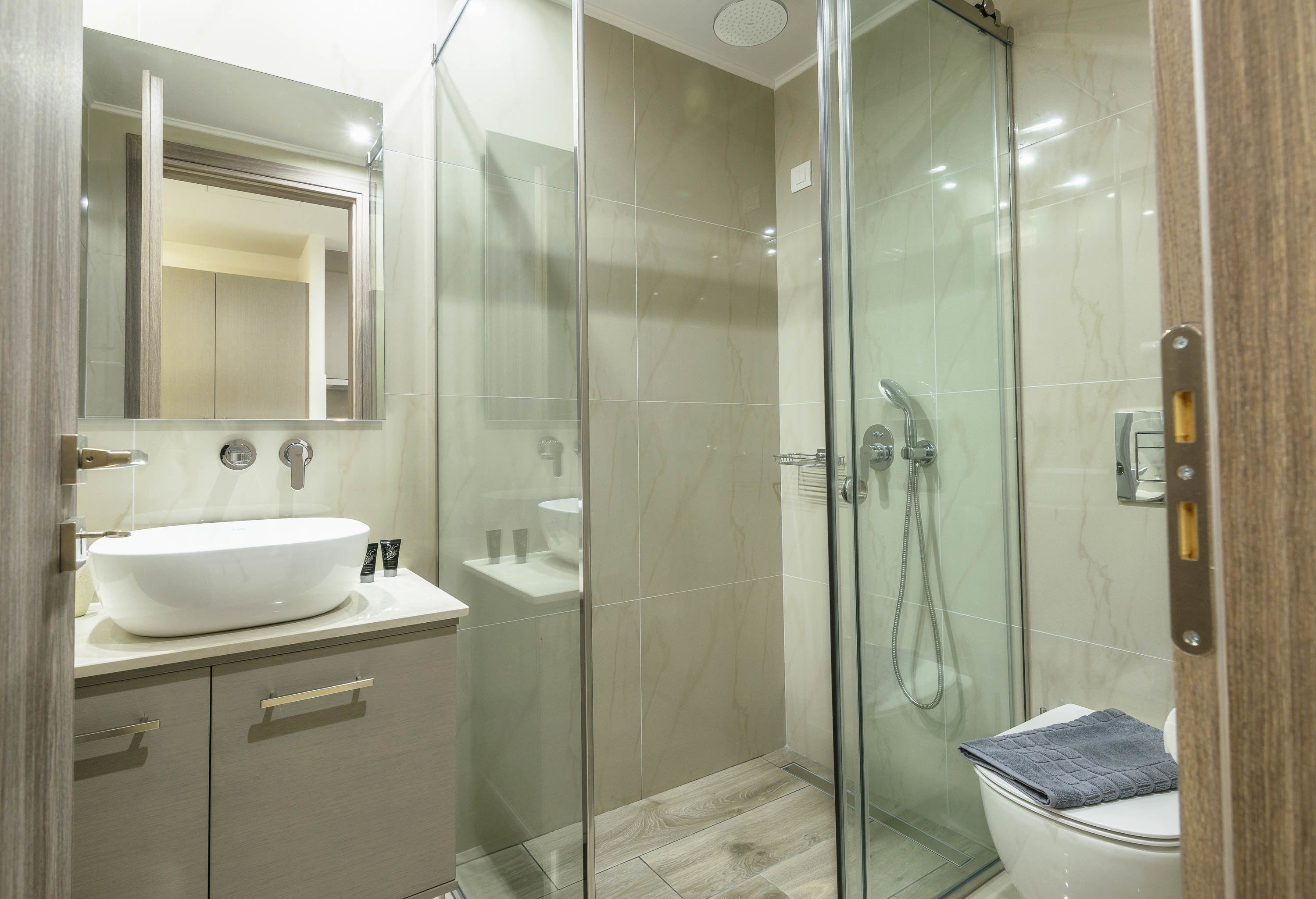 Ein modernes Badezimmer mit einer einteiligen Glasdusche, einem weißen Waschbecken und einer Toilette.
