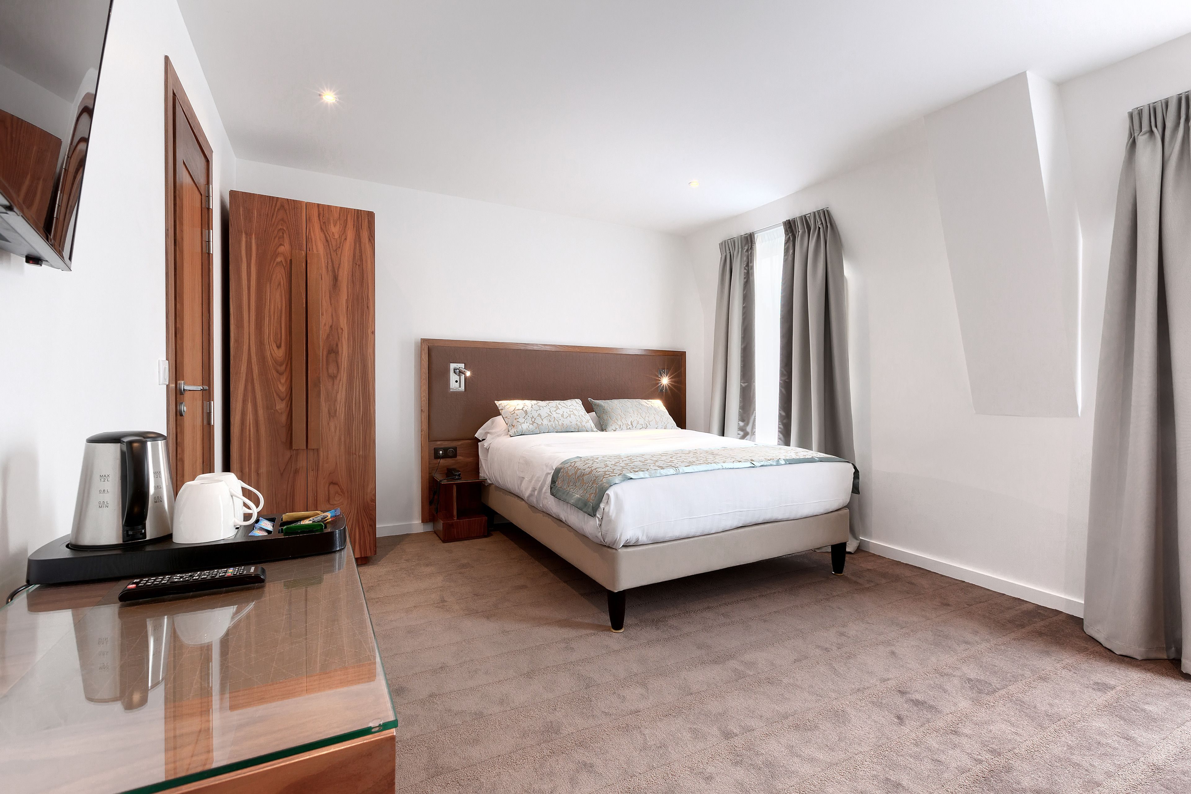 A hotel room with a bed, bedside table, and a coffee maker.