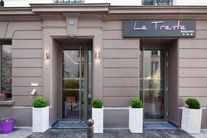 Un edificio con un letrero que dice "Le Trete Batignolles" y el número "30" sobre la entrada.