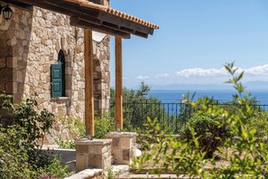 A stone building with a wooden balcony, a green door, and a view of the sea. - Joanna's Stone Villas (Zakynthos)
