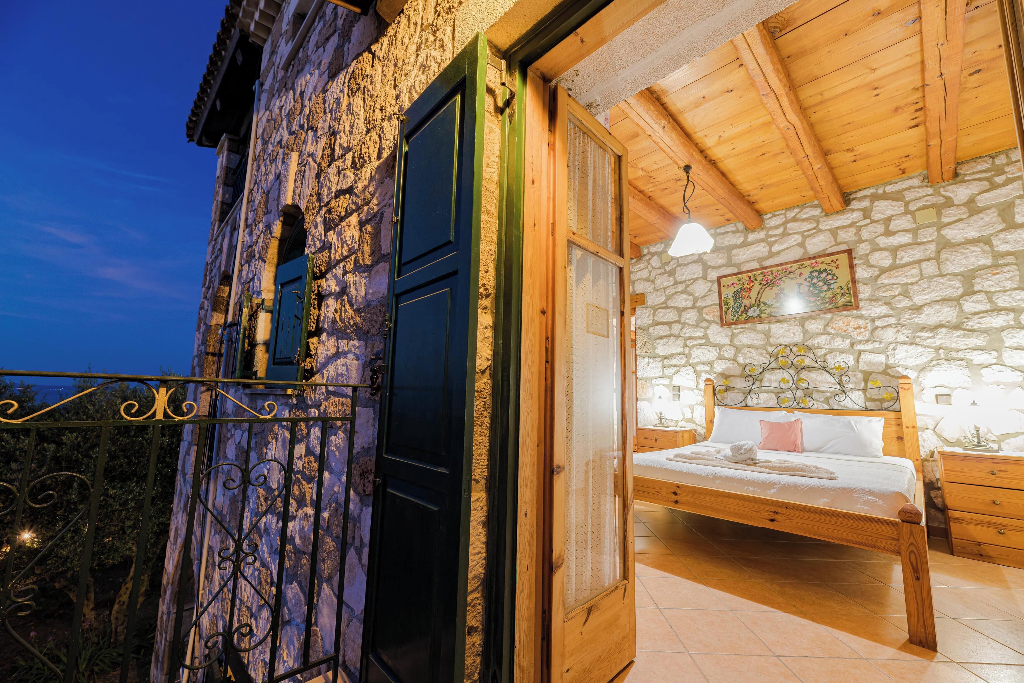 A stone building with a wooden balcony, a bed with a wooden headboard, and a night sky.