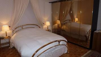 A bedroom with a bed, bedside lamps, a mirror, and a wardrobe.