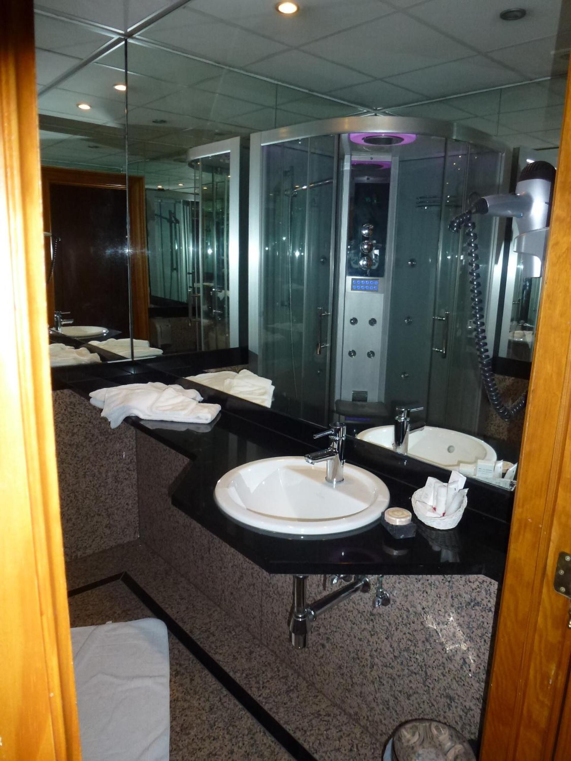 A modern bathroom with a large mirror, two sinks, a shower, and a glass-enclosed shower stall.