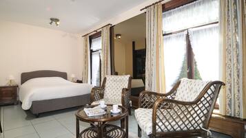 A bedroom with a bed, two chairs, a small table, and curtains.