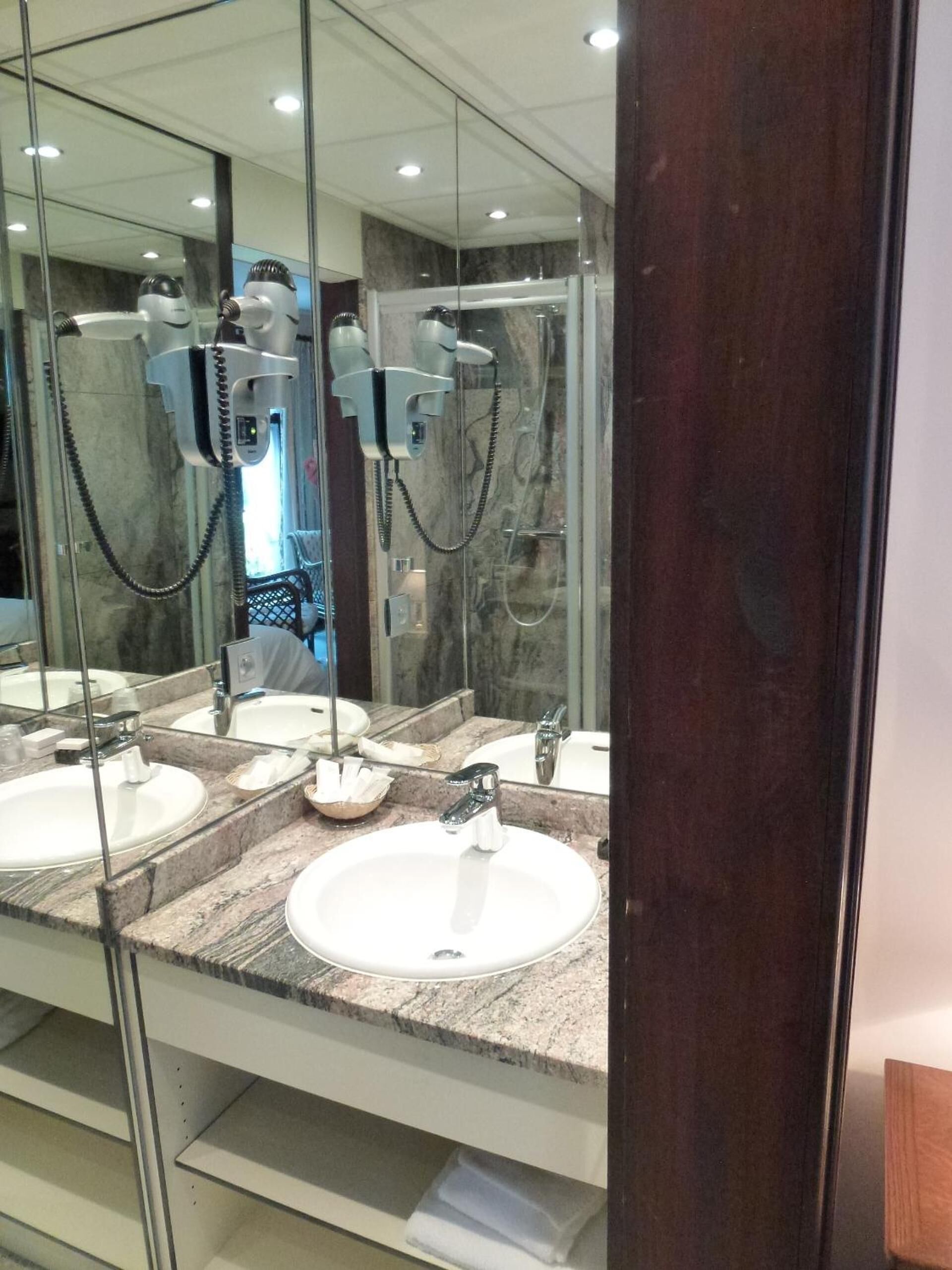 Casa de banho moderna com três lavatórios, um espelho grande e um secador de cabelo.