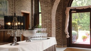 A table set with crystal glasses and bottles, a chandelier, and a view of a garden through a door. - Kasteel van Nieuwland (Aarschot)