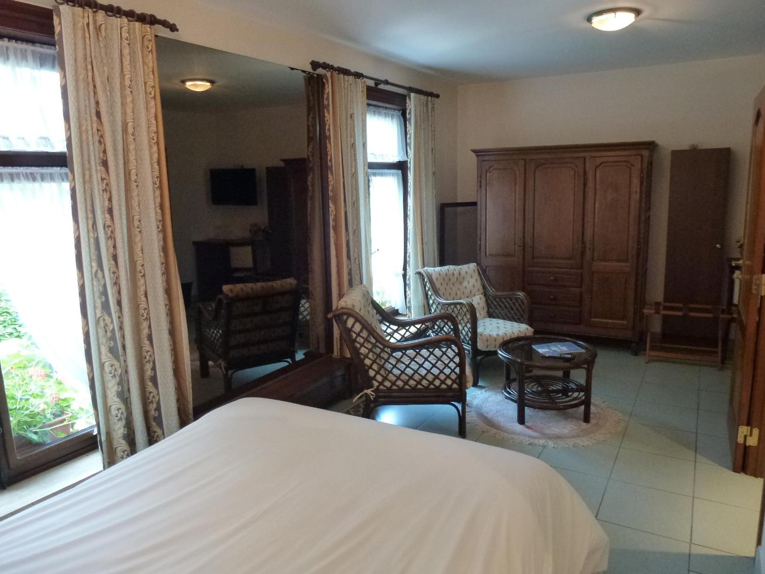 A room with a bed, two armchairs, a small table, and a wardrobe.