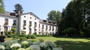 A large building with multiple windows and a well-maintained garden with white flowers. - Kasteel van Nieuwland (Aarschot)