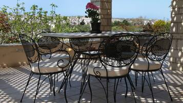 Relax on the patio with a round table and six comfortable chairs, surrounded by lush greenery and a beautiful potted plant.