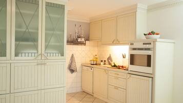 Uma cozinha com armários brancos, painel de azulejos e micro-ondas.