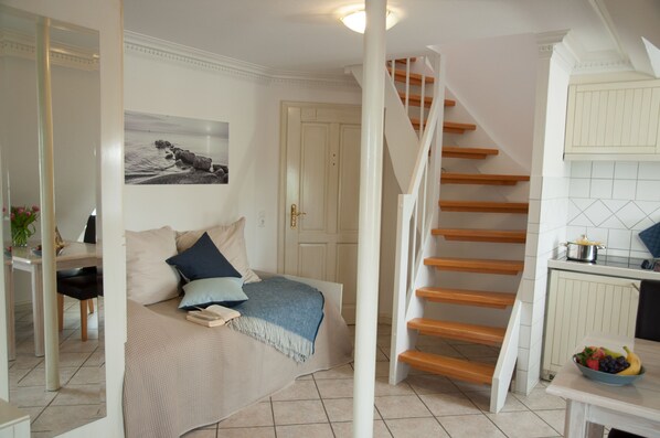 A bedroom with a bed, a nightstand, and a window. There is a staircase leading to the upper floor. - Freie Sicht Das Nordsee-Gesundheitshaus 1 (Dagebuell)