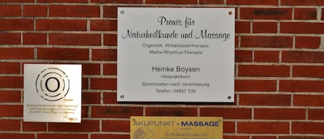 A signboard for a Naturheilkund clinic and massage center, including contact details and a logo.
