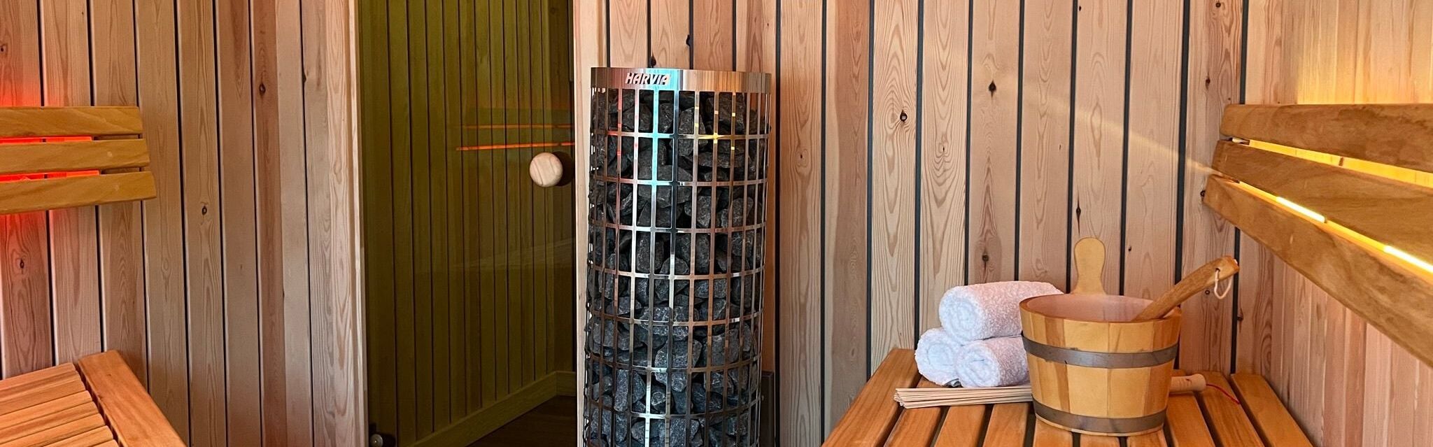 A sauna room with a wooden bench, a sauna heater, and towels.