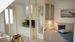 A cozy bedroom with a bed, a bedside table, and a TV. - Freie Sicht Das Nordsee-Gesundheitshaus 1 (Dagebuell)