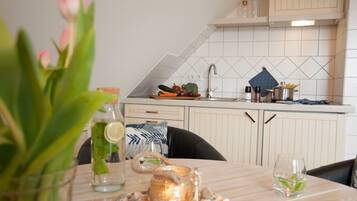 Een moderne keuken met witte kastjes, een betegelde achterwand en een eettafel met een bloemenvaas.