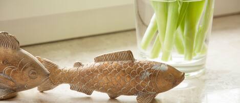 A fish-shaped decoration on a kitchen counter next to a glass containing green vegetables.