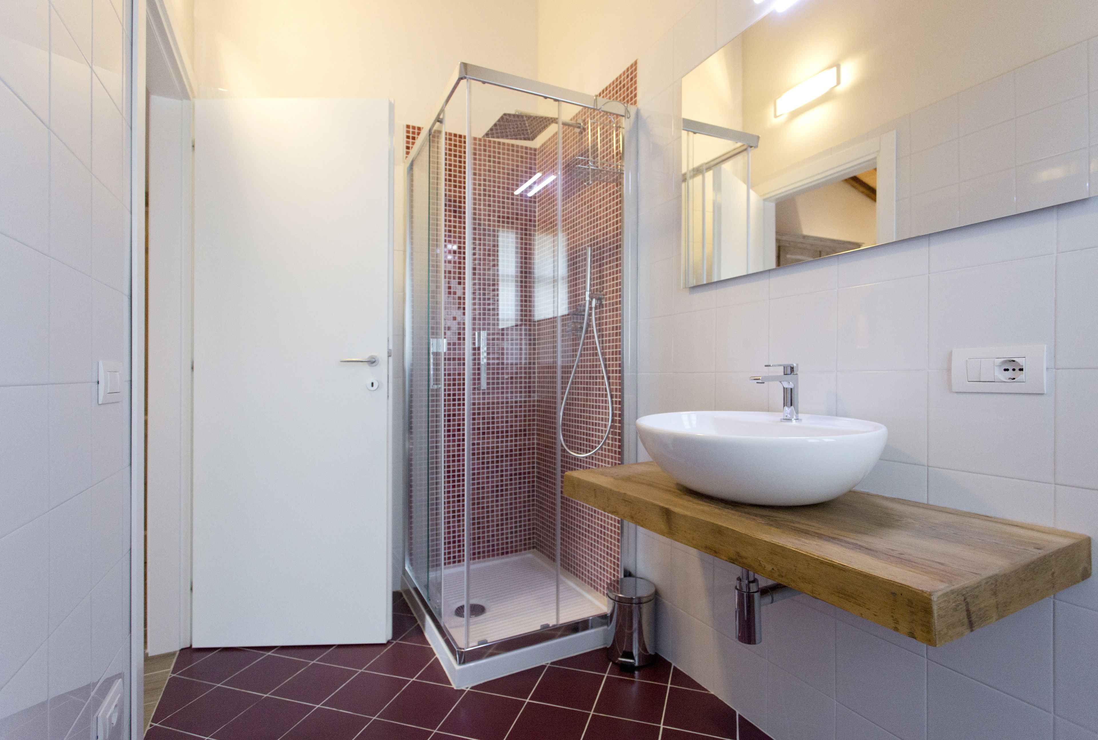 A modern bathroom with a glass-enclosed shower, a white sink, and a wooden countertop.