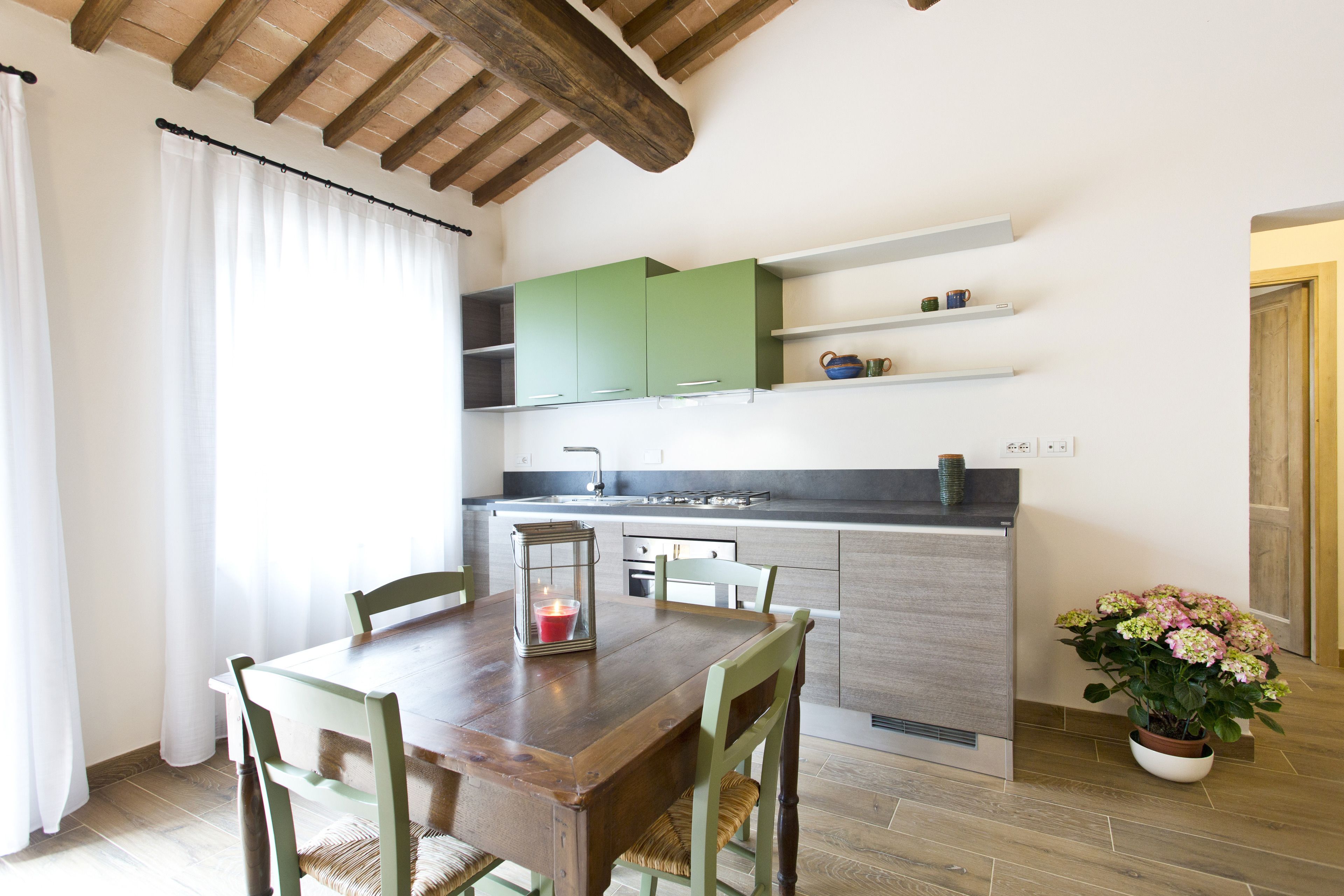 Un coin repas avec une table et des chaises en bois, une bougie et une plante en pot.