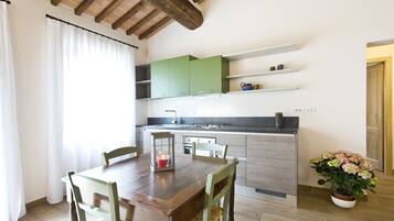Un coin repas avec une table et des chaises en bois, une bougie et une plante en pot.