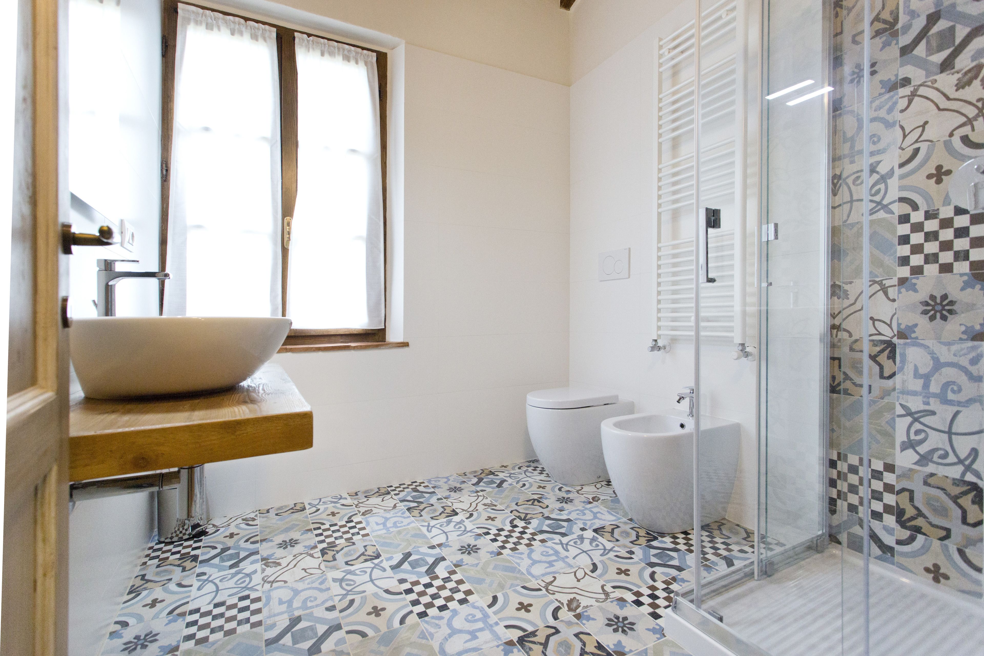 Une salle de bain comprenant un grand lavabo sur colonne, des toilettes et un espace douche.