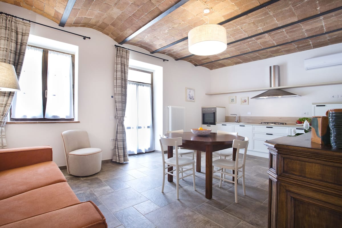 A modern kitchen with white cabinets, a dining table, and a sofa.