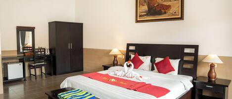 Ein Hotelzimmer mit Bett, zwei Nachttischen, einem Schreibtisch, einem Sessel, einem Kleiderschrank und einem Gemälde an der Wand.