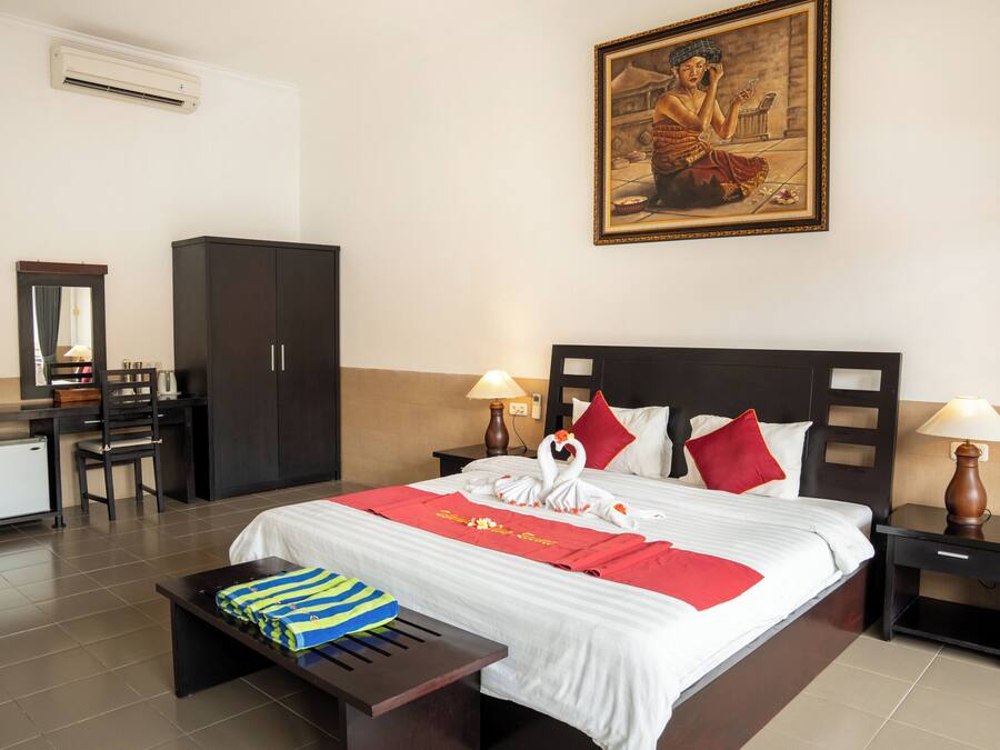 Habitación de hotel con cama, dos mesitas de noche, escritorio, silla, armario y un cuadro en la pared.