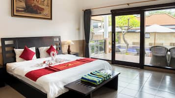 Ein Hotelzimmer mit Bett, einem Gemälde, einem Balkon mit Stühlen und Blick auf den Pool.