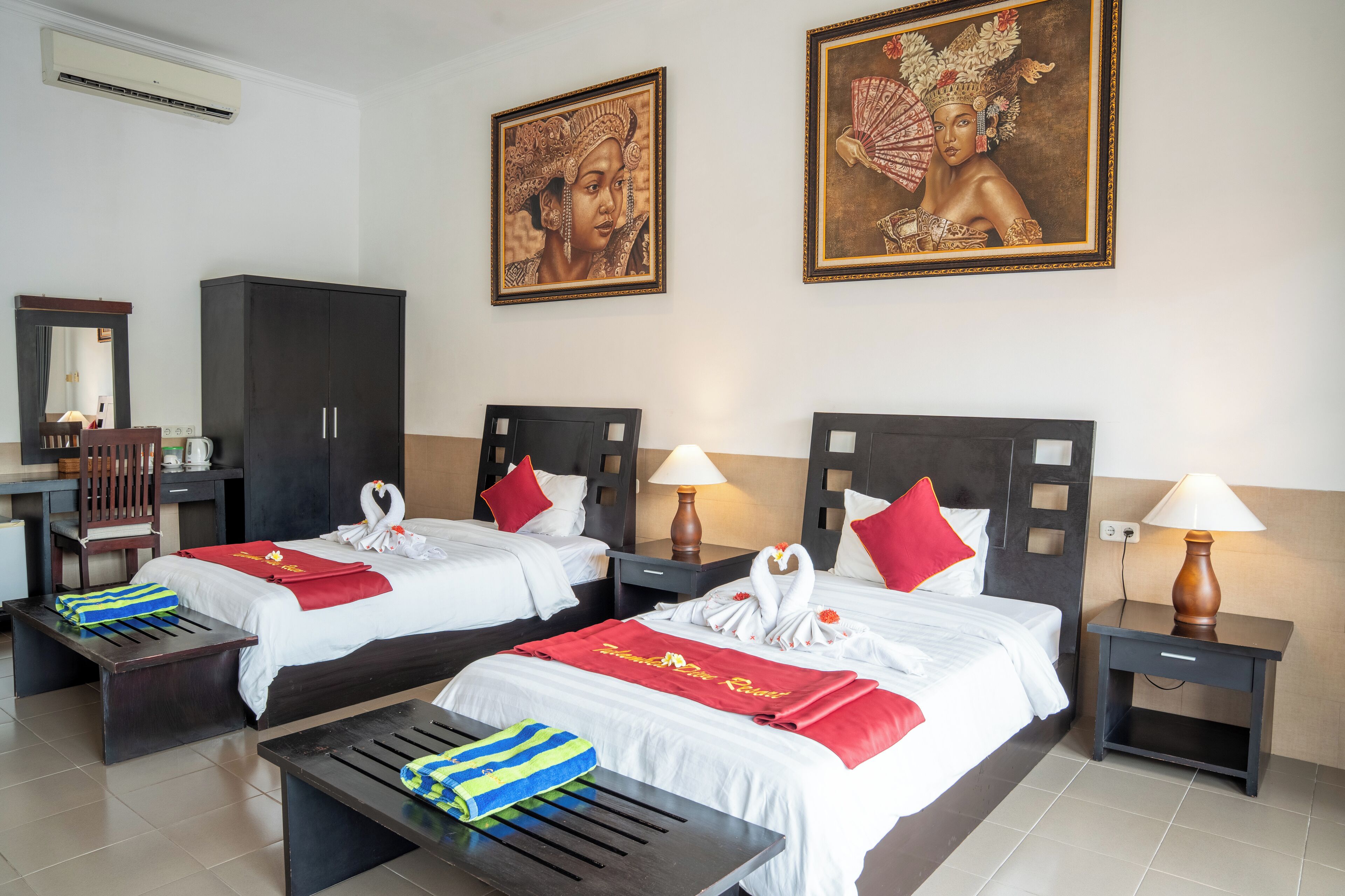 Ein Hotelzimmer mit zwei Betten, einem Schreibtisch, einem Kleiderschrank und Kunstwerken an den Wänden.