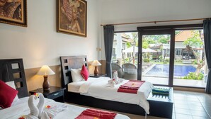 A hotel room with two beds, a view of the pool, and a dining area with outdoor seating.