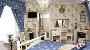 Een slaapkamer met een bed, een bureau, een stoel, een dressoir en een spiegel.