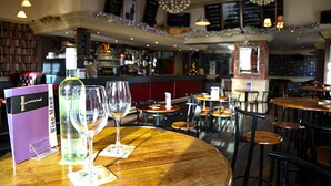 Een restaurantinterieur met ronde tafels, stoelen en een bar.