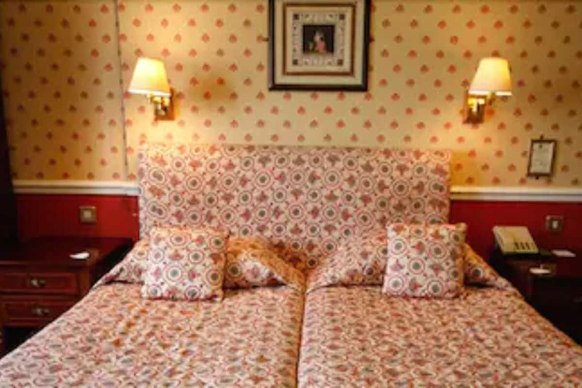 Een hotelkamer met een groot bed, twee nachtkastjes, een wandlamp en een nachtkastje.