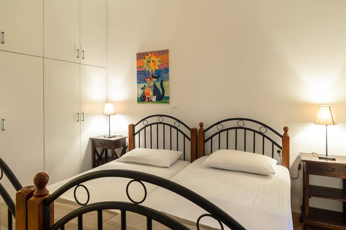 A double bed with a wooden headboard, a nightstand with a lamp, and a painting on the wall.