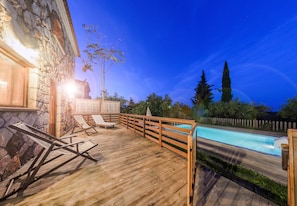 Une terrasse en bois avec des chaises longues et une piscine.