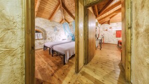 A rustic room with wooden beams, stone walls, and two beds. - Parys Villas (Zakynthos)