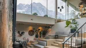 Un intérieur moderne avec un escalier menant à un balcon d’où l’on peut admirer les montagnes.