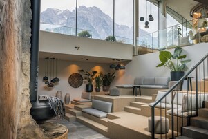 Et moderne interiør med en trappe, der fører op til en balkon med udsigt til bjerge.
