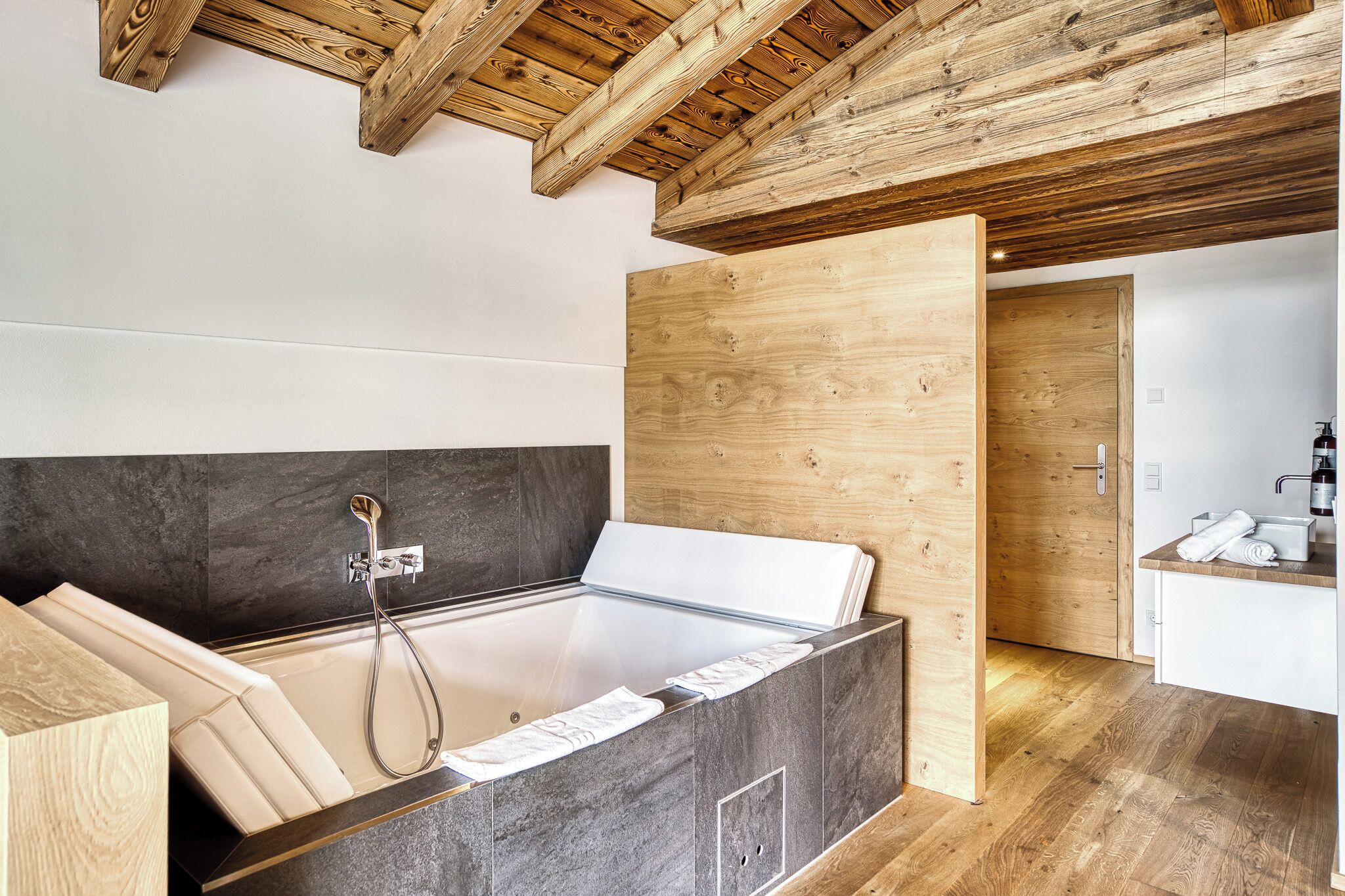 Ein modernes Badezimmer mit Holzboden, einer Badewanne und einem Waschtisch mit Becken.