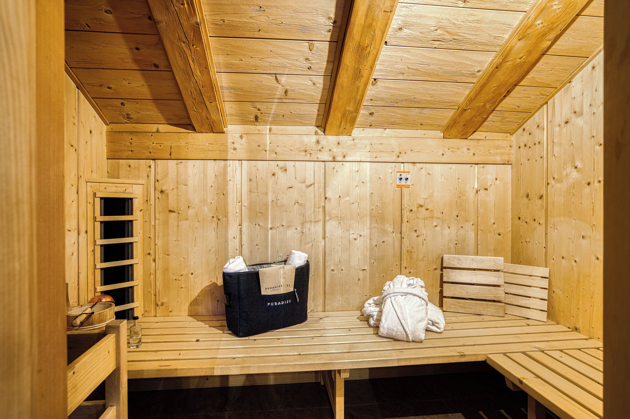 Un sauna de madera con bancos, un perchero para toallas y una bolsa de almacenamiento.