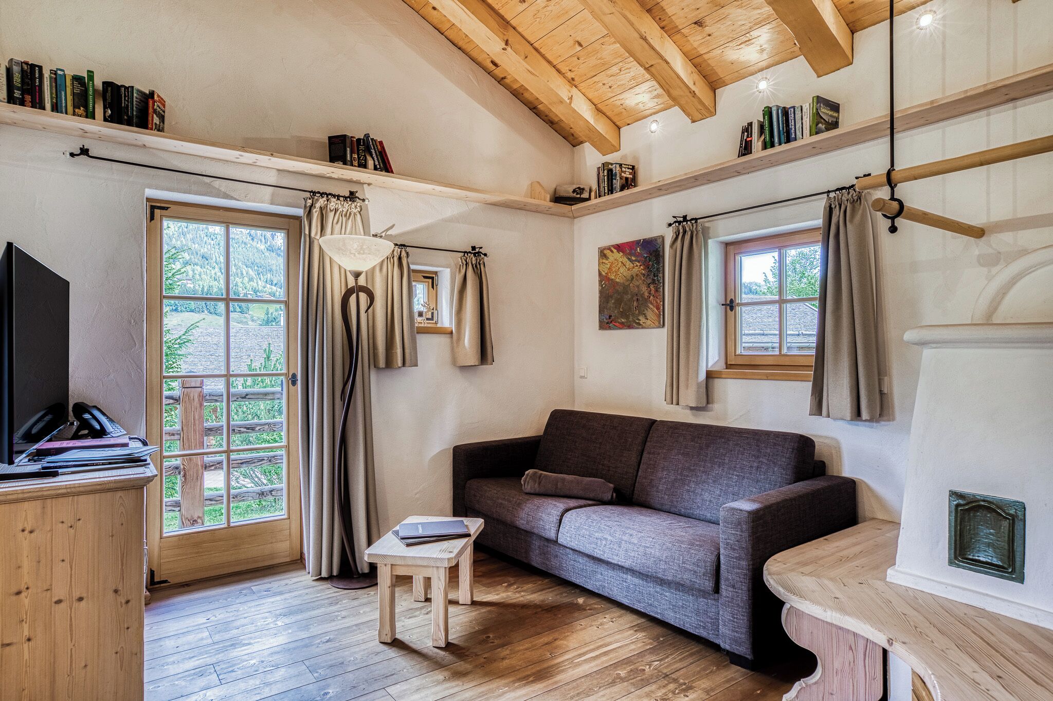 Una habitación acogedora con suelo de madera, un sofá, una mesita, un televisor y una chimenea.
