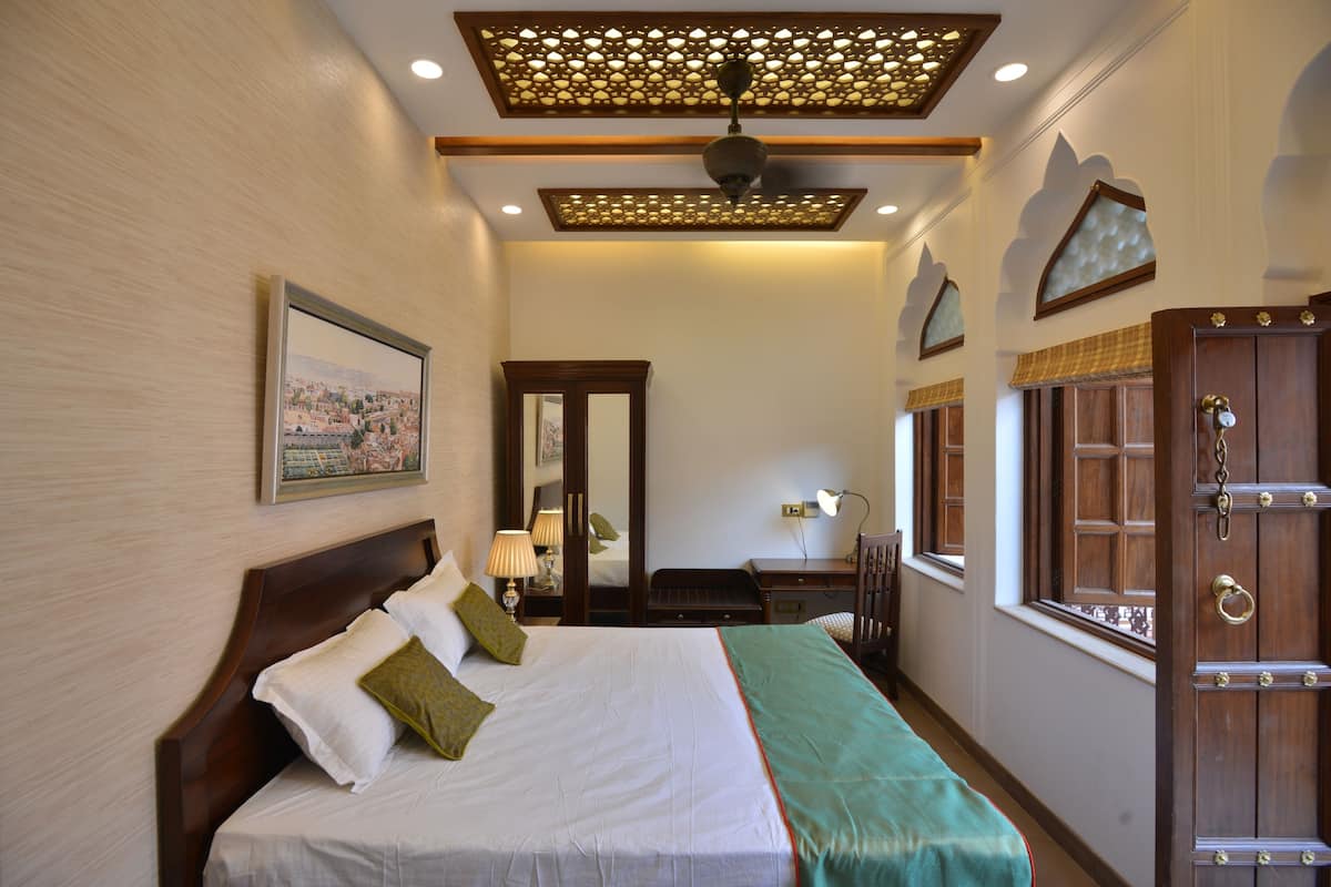 Habitación de hotel con una cama grande, un escritorio, una silla, un armario y una ventana.