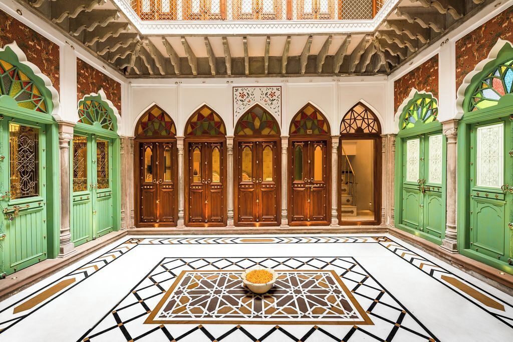 Una habitación con piso estampado, puertas verdes y un elemento decorativo central.