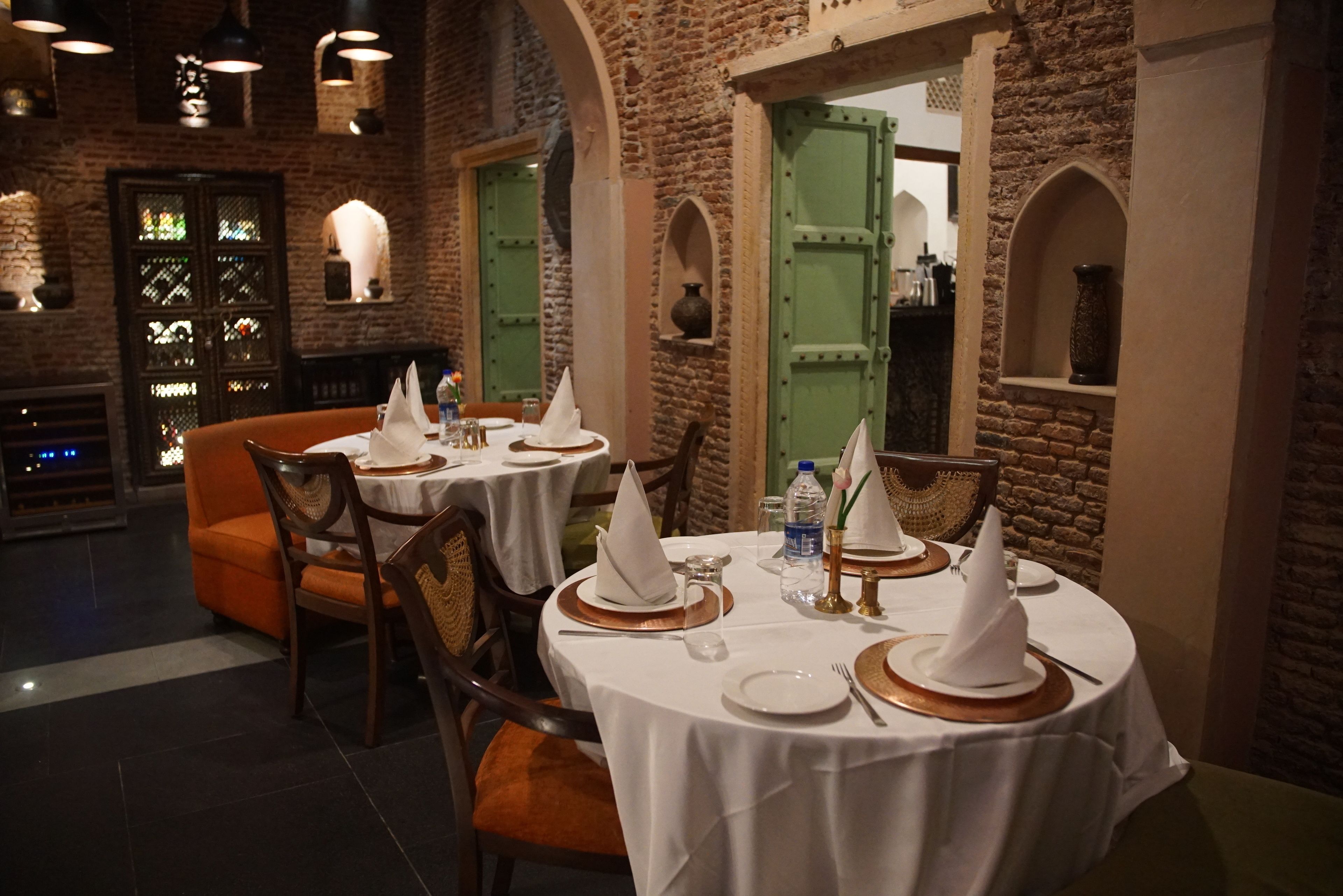 A restaurant with round tables set for dining, featuring white tablecloths, napkins, and cutlery.