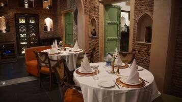 A restaurant with round tables set for dining, featuring white tablecloths, napkins, and cutlery.