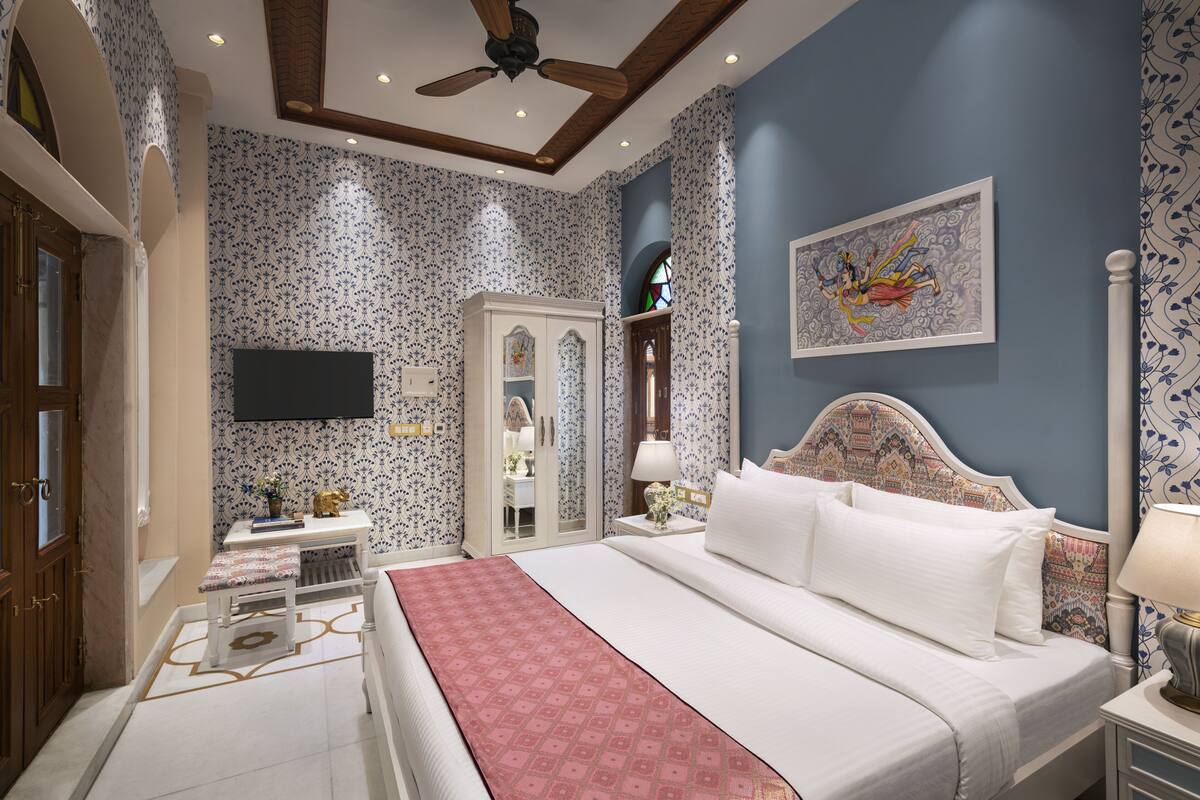 Un dormitorio con una cama grande, un televisor en la pared y una puerta que da a otra habitación.