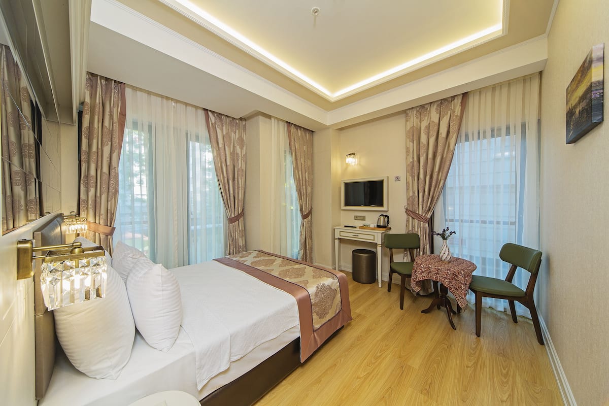 A hotel room with a bed, desk, chair, and a television.