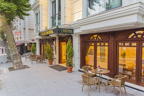 A hotel with a classic facade, outdoor seating area with wicker chairs, and large windows. - Grand Naki Hotel (Istanbul)