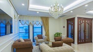 A spacious living room with a chandelier, two sofas, a coffee table, and a large window with curtains. - Grand Naki Hotel (Istanbul)